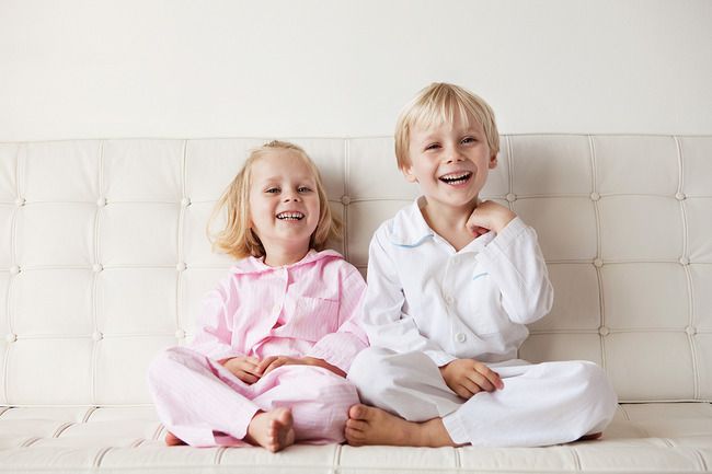 Young children in their pajamas sitting on the sofa